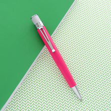 Load image into Gallery viewer, A pink retractable pen with chrome metal accents, placed diagonally on a split background of solid green and green-and-white chevron patterned paper.