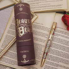 Load image into Gallery viewer, Pen with intricate design in a brown cylindrical packaging on an open book.