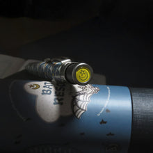 Load image into Gallery viewer, Close up to the pen's top disk on a dark background. It shows a half moon and a star on a yellow background.