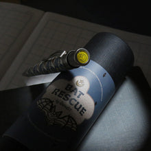 Load image into Gallery viewer, The pen leaning on the gift tube, with the focus showing the top disk on the pen with a print of a star and half moon.