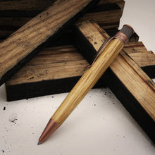 Load image into Gallery viewer, Side view of the The Retro 51 Tornado Woodworks Bourbon barrel Pen with an arrangement of small charred wood panels. The pen's barrel is made of wood and it has stonewood copper accents.