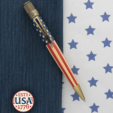 Load image into Gallery viewer, Front view of the rollerball pen. Placed on a textured blue background split by a white background with stars. A badge at the bottom left reads: ESTD USA 1776.