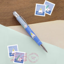 Load image into Gallery viewer, Side view of the pen on a blue and brown background with postage stamps
