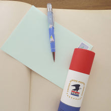 Load image into Gallery viewer, Side view of the pen arranged on a notebook with an envelope and the gift tube.