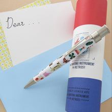 Load image into Gallery viewer, Side view of the pen leaning on the gift tube on top of blue, white, and yellow pattern paper sheets.
