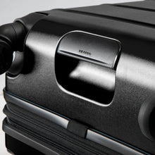 Load image into Gallery viewer, Angled close up to the bottom panel on the black hard shell suitcase. It features a grab handle.