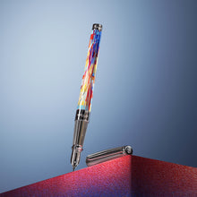 Load image into Gallery viewer, The image shows The Graff'ty Fountain Pen with the cap set to the side, styled on a blue background, with the pen standing on a blue and red stand.