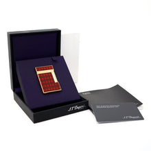 Load image into Gallery viewer, The S.T. Dupont Vertiigo II lighter with a red and brown argyle pattern and gold trim, presented in an open black presentation box with a purple insert, alongside a brand card and booklet on a white background.