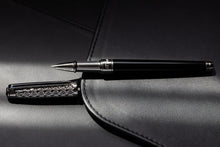 Load image into Gallery viewer, The rollerball pen with the cap set to the side. Both are laid on soft pieces of black leather on a dim light.