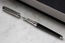 Load image into Gallery viewer, Front view of the fountain pen with the cap set to the side, laid on a marbled surface.
