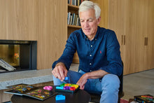 Load image into Gallery viewer, Man playing with the IQ Square puzzle in a living room.