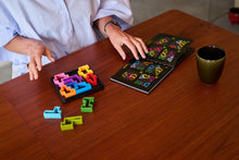 Load image into Gallery viewer, Person playing with the IQ puzzle game on a wooden table