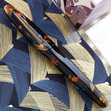 Load image into Gallery viewer, Front view of the fountain pen with the cap on. Laid on a paper printed with line patterns.