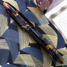 Load image into Gallery viewer, Side view of the fountain pen with the cap on. Laid on a paper printed with line patterns.