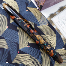 Load image into Gallery viewer, Back view of the fountain pen with the cap on. Laid on a paper printed with line patterns.