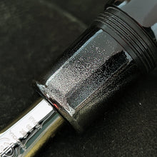 Load image into Gallery viewer, Close up to the grip section, focused on the silver powder sprinkled on it.