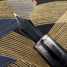 Load image into Gallery viewer, Close up to the grip section and the feed on the nib. The grip section features a black urushi background with a gentle gradient of silver powder.