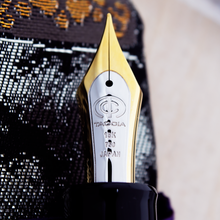 Load image into Gallery viewer, Close up to the fountain pen nib's engraving, featuring the Taccia logo, 18K, 750, JAPAN.