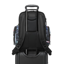 Load image into Gallery viewer, Back panel view with the backpack's attachment strap holding it on to a suitcase's handle.