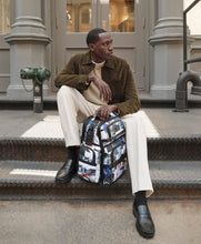 Load image into Gallery viewer, A young man sitting on an urban setting with the backpack in front of him.