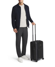 Load image into Gallery viewer, A young man holding the extended handle of the suitcase.