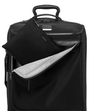 Load image into Gallery viewer, The backpack inside its folded bag, being tucked inside the front pocket of a suitcase.