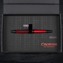Load image into Gallery viewer, The fountain pen placed on the presentation box slot. The area around the pen has a print of different years in black, and the text "CAPLESS 60TH ANNIVERSARY" in red.