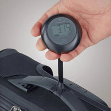 Load image into Gallery viewer, The scale tied to a suitcase's top handle, and being lifted by a hand to weigh it.