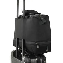 Load image into Gallery viewer, The black duffle bag's back panel slipped through a suitcase's telescopic handle.