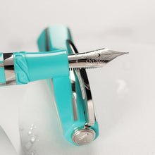 Load image into Gallery viewer, Close up to the Visconti Divina Elegance Wave Fountain Pen nib leaning on the cap. The medal at the top of the cap has the Visconti V logo engraved on it.