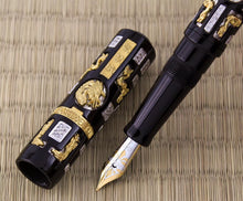 Load image into Gallery viewer, Close up to the fountain pen nib with the cap set next to it. The pen is made of black lacquer, with small silver and gold vermeil rectangles and shapes featuring designs and diamond paves encrusted around it.