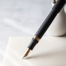 Load image into Gallery viewer, Black fountain pen with gold nib on a light background