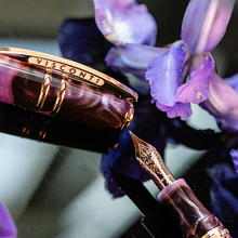 Load image into Gallery viewer, Visconti Homosapiens Iris Garden Pen Close Up to the fountain pen nib and cap on a dark background with lavender flowers.