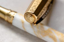 Load image into Gallery viewer, Close up and focus on the top of the cap for the The Visconti Il Magnifico Calcatta Gold Pen. It has a medal with the Visconti V logo.