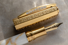 Load image into Gallery viewer, Close up to the cap and Fountain Pen Nib on the Visconti Il Magnifico Calcatta Gold Fountain Pen. The cap has some engraved designs of some fleur de lis and other markings.