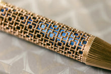 Load image into Gallery viewer, Close up to the barrel of the Visconti Looking East Fountain Pen. It has a pearlescent blue barrel with a golden overlay with square designs.