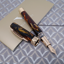 Load image into Gallery viewer, Top view of the Fountain Pen with the cap off and set to the side. It is laid a top the presentation box and the booklet included.
