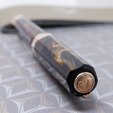 Load image into Gallery viewer, Angled view of the top of the cap. it has a medal with the Visconti logo engraved on it.