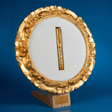 Load image into Gallery viewer, The pen rests in its ornamental stand, in the shape of an elegant circular frame surrounding a white background. The stand is set on a blue background.