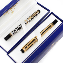 Load image into Gallery viewer, Front view of the gold and silver fountain pens resting in their presentation boxes. Both have a black lacquer body. One has a silver overlay design with leaves and a few golden accents. The other one a gold overlay design with stripes.
