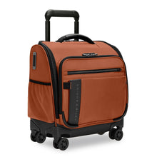 Load image into Gallery viewer, Angled front view of the canyon orange underseat cabin spinner suitcase with black accents. It features two zipper-closing pockets, and one open pocket at the side and front panels.