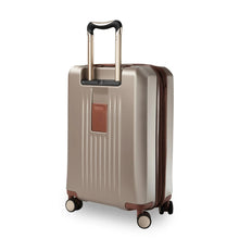 Load image into Gallery viewer, Angled back panel view of the beige suitcase with the telescopic handle extended.