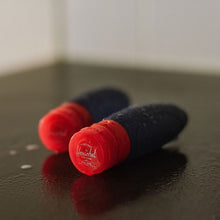 Load image into Gallery viewer, Angled view of the two navy travel bottles on a black surface, surrounded by water droplets.