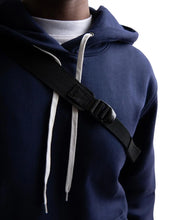 Load image into Gallery viewer, Close up to a young man's torso while carrying the sling bag.