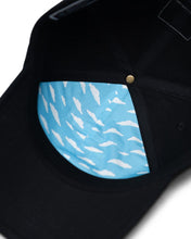 Load image into Gallery viewer, Interior close up to the black Sylas cap. It has a partial interior lining piece of sky blue fabric with white clouds