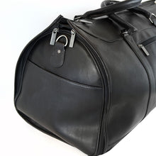 Load image into Gallery viewer, Close up to the side panel of the black garment duffle bag. It features a pocket and a stainless steel ring to attach the shoulder strap clip.
