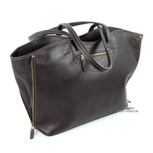 Load image into Gallery viewer, Angled front view of the brown leather tote bag. The shoulder straps are resting across the top.