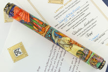 Load image into Gallery viewer, Front view of the Fountain Pen set atop the included certificates. The Artist Signature is of Natasha Kurkina. The pen has a detailed miniature Russian-Lacquer Art design. This side shows Gandalf with his pipe, a set of fireworks, the found door to a Hobbit house, and a red dragon's wing.