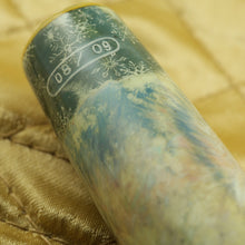 Load image into Gallery viewer, Close up to the edition number painted on the pen. This one reads 08 / 09. The background shows some thin designs of snowflakes on a blue background.