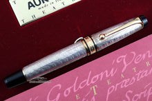 Load image into Gallery viewer, Front view of the pen with the cap on. The body is silver with golden accents on the clip and cap ring. The top of the cap and bottom of the barrel are made of black resin.